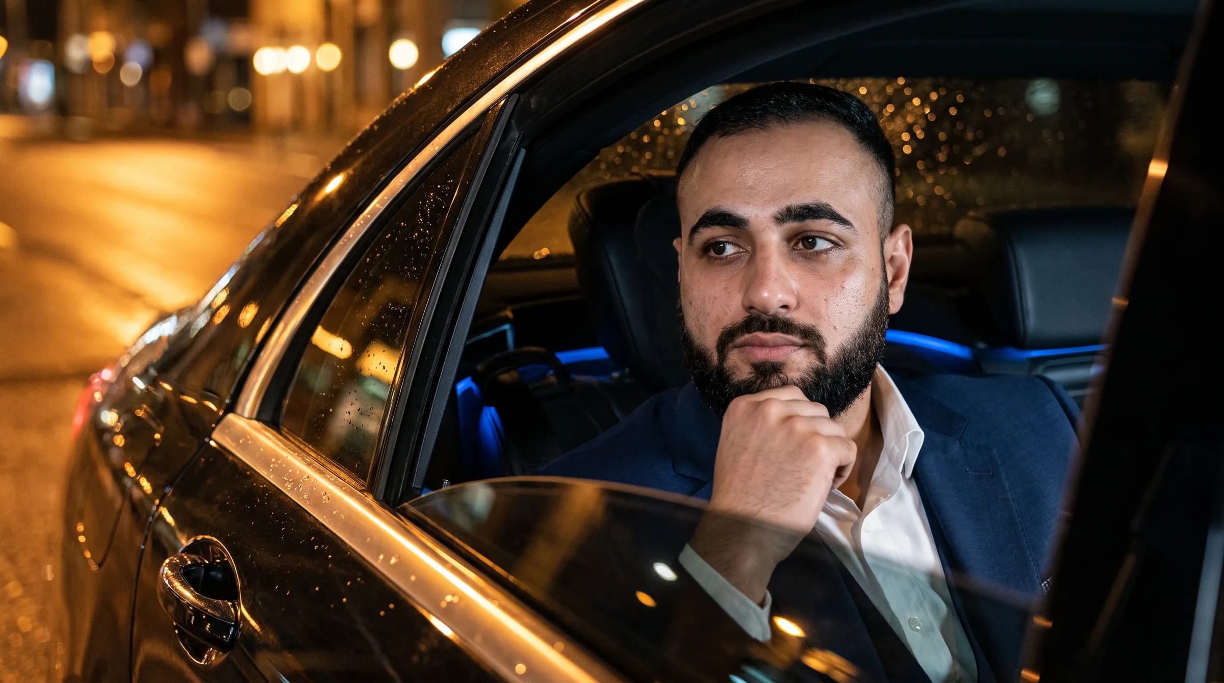 Hassan Pasha in the rear seat of a car at night, city lights outside