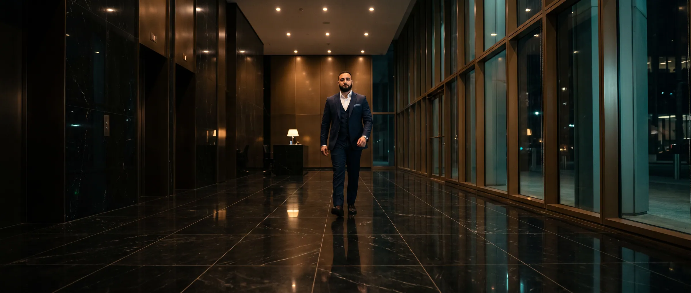 Hassan Pasha walking through a dark marble lobby at night
