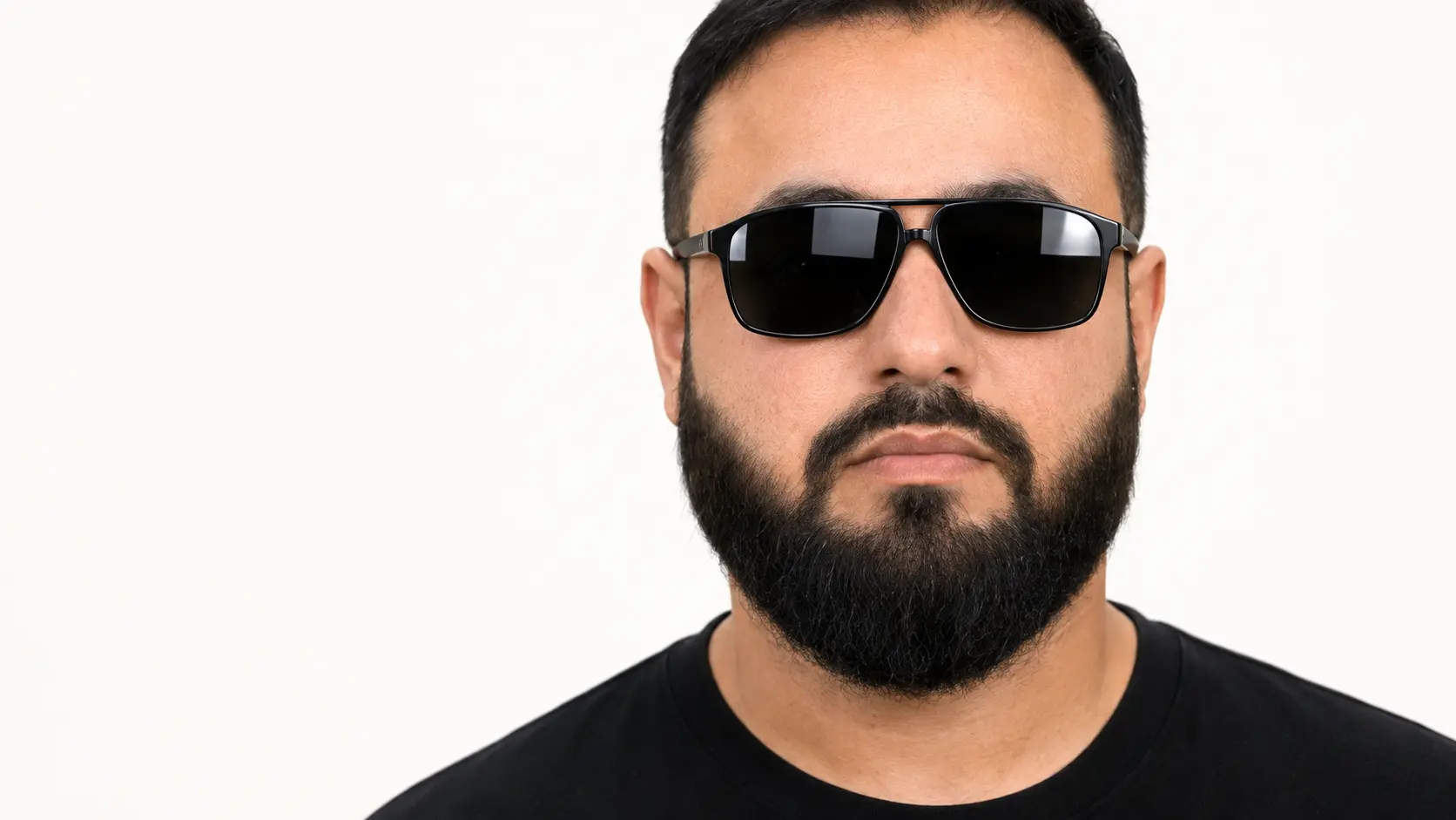 Hassan Pasha, founder and creative director, wearing black sunglasses in a white studio
